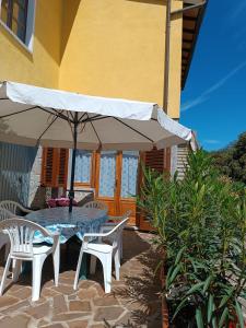 eine Terrasse mit einem Tisch, Stühlen und einem Sonnenschirm in der Unterkunft Appartamento nel parco in Marciana