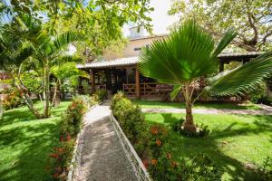 uma casa com um jardim com árvores e flores em Pousada Bicho Preguiça em Pipa