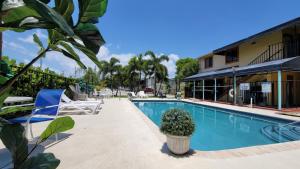 a swimming pool with two chairs and a building at Sunny Palms Inn in Lake Worth