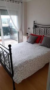 Schlafzimmer mit einem Bett mit roten Kissen und einem Fenster in der Unterkunft Fantástico apartamento con piscina en Tossa de Mar in Tossa de Mar