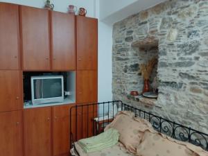 sypialnia z telewizorem i kamienną ścianą w obiekcie Myrtle w mieście Engares