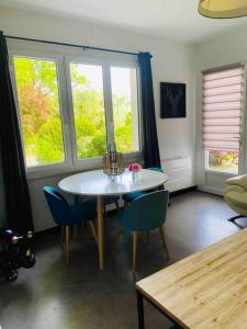 salon ze stołem, krzesłami i oknami w obiekcie Maison - Terrasse - Jardin - Foret landaise w mieście Préchacq
