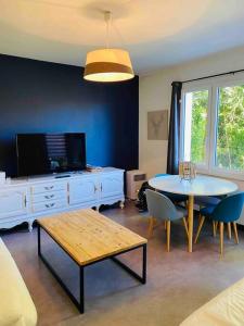 a living room with a table and a tv at Maison - Terrasse - Jardin in Préchacq