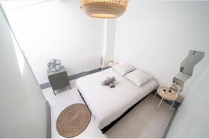 a small white bedroom with a bed and a chair at Le San Diego - Appartement 4 pers Oullins-Lyon in Oullins