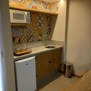 eine kleine Küche mit einer Spüle und einer Mikrowelle in der Unterkunft Quinta Santa Bárbara Eco Resort in Pirenópolis