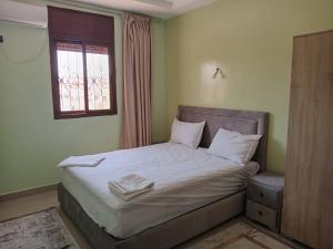 a bedroom with a bed with white sheets and a window at Résidence Jannat in Ouarzazate