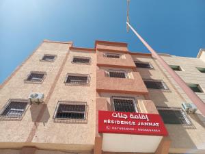 un bâtiment avec un panneau sur son côté dans l'établissement Résidence Jannat, à Ouarzazate