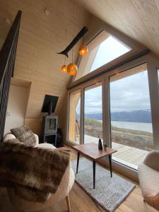 a living room with a couch and a table and a large window at Hengifosslodge Tiny Houses in Egilsstaðir