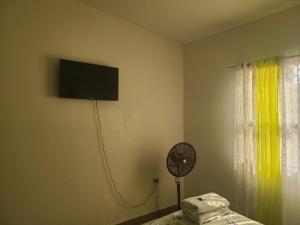 a room with a tv on the wall and a fan at Hospedaje Casa de Luna in Tegucigalpa