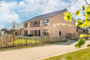 a brick house with a fence in front of it at De Hoog Velden 15 in Overpelt