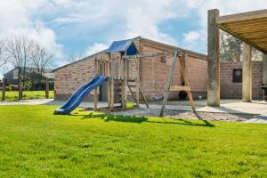 a playground with a blue slide in a yard at De Hoog Velden 15 in Overpelt