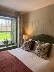 a bedroom with a bed with pillows and a window at The Red Lion Inn Alnmouth in Alnmouth