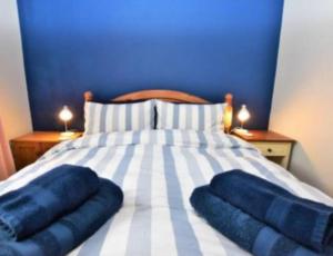 a bed with two blue pillows on top of it at Swallow's Roost Chapel in Chacewater