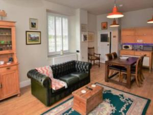 a living room with a black leather couch and a table at Swallow's Roost Chapel in Chacewater