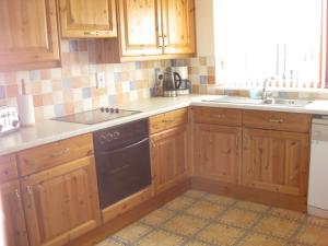 a kitchen with wooden cabinets and a black dishwasher at Ardmuir in Turriff