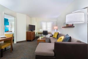 ein Wohnzimmer mit einem Sofa und einem TV in einem Zimmer in der Unterkunft Residence Inn by Marriott St. Louis Downtown in Saint Louis