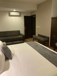 - une chambre avec un grand lit et un canapé dans l'établissement Hoteles Unico Express, à León