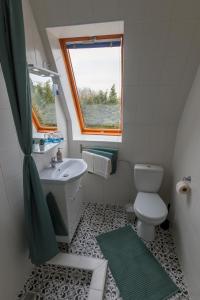 a bathroom with a toilet and a sink and a window at Kétpáva Vendégház in Igal