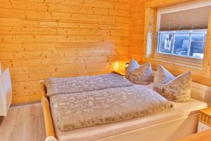 uma cama num quarto de madeira com uma janela em Ferienwohnungen an der Hauptspree em Kolonie