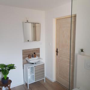 uma casa de banho com um lavatório, um espelho e uma porta em Moin in Turckheim em Turckheim