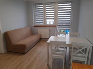 a living room with a couch and a table and chairs at Przytulny Apartament na Strzeleckiej in Płock +3 photos
