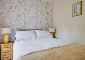 a bedroom with a bed with a floral wallpaper at The Dairy in Llanerchymedd