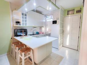 a kitchen with white cabinets and a counter with stools at eldorado blue in Playa de las Americas