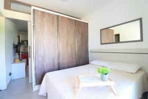 1 dormitorio con cama blanca y pared de madera en Maravilhoso apto wi-fi e vista para o mar - HB06F, en Florianópolis