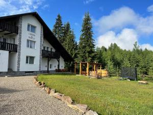 a large white building with a grass field next to it at Casa Bradut in Dorna Arini