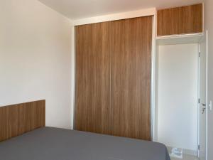 - une chambre avec un lit et des placards en bois dans l'établissement Apto novo, com ar, acesso rápido ao centro, à Uberlândia