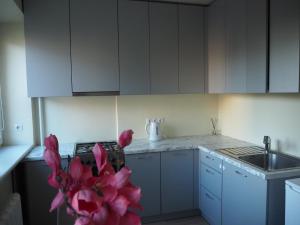 een keuken met witte kasten, een wastafel en roze bloemen bij B&K apartments in Panevėžys