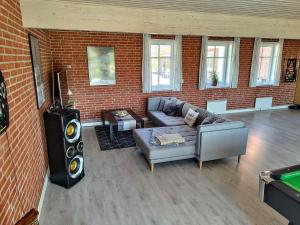 a living room with a couch and a tv in a brick wall at Ferielejlighed Rubjerg Præstegård in Løkken