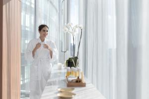 Eine Frau in Weiß steht in einem Zimmer mit Fenster in der Unterkunft The Ritz-Carlton, Mexico City in Mexiko-Stadt