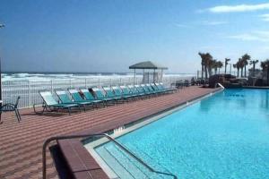 uma piscina com cadeiras e o oceano ao fundo em Amazing Studio on Daytona Beach em Daytona Beach