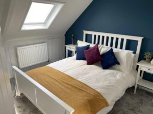 a bedroom with a white bed with colorful pillows at Tenby hideaway - by the beaches in Tenby