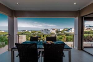 a dining room with a table and chairs on a balcony at Copina Holiday Home in De Kelders