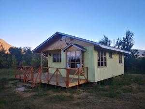 a green tiny house with a deck in a field at Cabaña Jacarandá in Salamanca