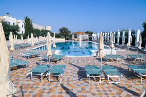 a swimming pool with lawn chairs and umbrellas at Calanca Apulian Residence in Torre Santa Sabina