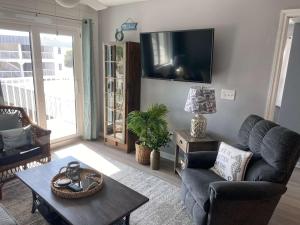 a living room with a couch and a tv on the wall at Gulf Shores Plantation 4307 by ALBVR - New Upgraded Condo and Building - Great Amenities in Gulf Highlands