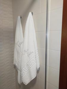 Er hangen twee witte handdoeken aan een douchecabine. bij ATICO CALDAS in Caldas de Reis
