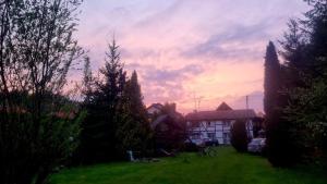 zachód słońca na dziedzińcu z drzewami i domem w obiekcie Mazurski Kubryk w mieście Ruciane-Nida