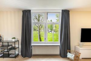 una sala de estar con una ventana con cortinas grises en Nummertje50, en Wommels