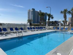 une piscine avec des chaises bleues et des palmiers dans l'établissement Grand Caribbean 205 by ALBVR - Condo has beautiful views of the Gulf and great rates, à Orange Beach