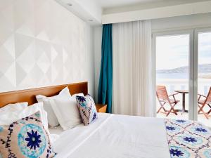 a bedroom with a bed with a view of the ocean at Grand Beach Hotel in Mikonos