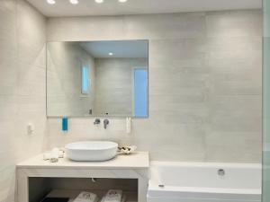 e bagno con lavandino, specchio e vasca. di Grand Beach Hotel a Mykonos Città