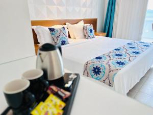 a hotel room with two beds and a coffee maker on a table at Grand Beach Hotel in Mikonos