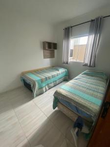 瓜拉圖巴的住宿－Casa região central Guaratuba，一间卧室设有两张床和窗户。