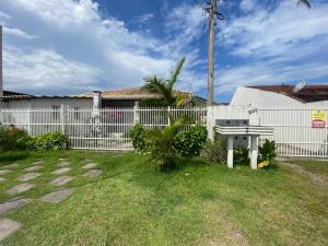 a white fence with a bench in a yard at Casa região central Guaratuba in Guaratuba