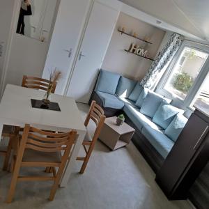a living room with a blue couch and a table and chairs at Mobil-Home Clos 14 à VIAS in Vias