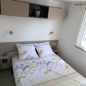 um quarto com uma cama com lençóis brancos e uma janela em Mobil-Home Clos 14 à VIAS em Vias